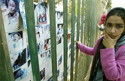 Una mujer repasa un mural con fotografías de las víctimas del terremoto de la semana pasada en Argelia, dispuesto en un cementerio para los familiares reconozcan a los muertos en el seismo.