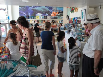 Varias personas mirando los productos que se ofertan en la tienda del Aquarium.