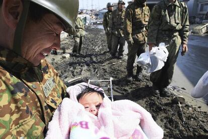 Un militar sostiene en brazos a un bebé en la ciudad de Ishimaki, en el norte de Japón.