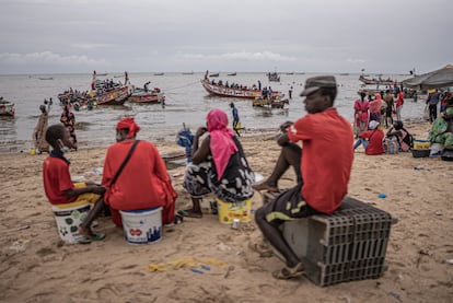 Un grupo de mujeres y jóvenes espera la llegada de los cayucos al puerto de Mbour, en Senegal, tras la jornada de pesca. Mbour es una localidad de tradición pesquera y en la que muchos migrantes han partido a lo largo de la historia en dirección a las islas Canarias.