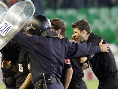 Rubinos Pérez y sus ayudantes salen del césped protegidos por la policía.
