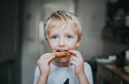 Un niño come una tostada con crema de cacahuete. 