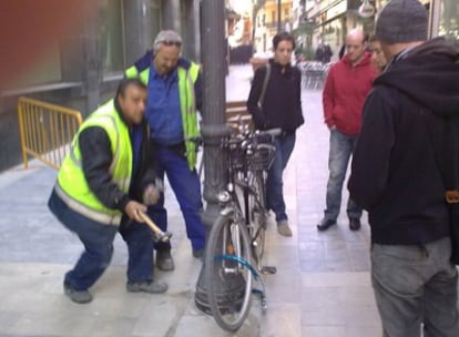 Operarios del Ayuntamiento de Valencia han confiscado por orden del concejal de Alumbrado, Juan Vicente Jurado, bicicletas encadenadas a las farolas en la calle de Moratín de Valencia. En la imagen, rompen los candados con un martillo.