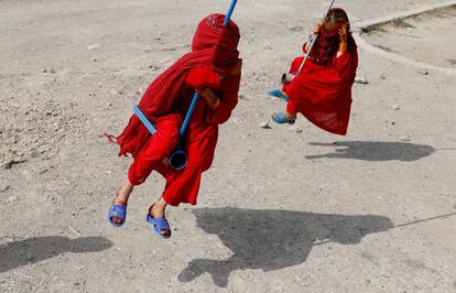 Niñas afganas se cubren el rostro mientras juegan en columpios en Kabul en 2019.