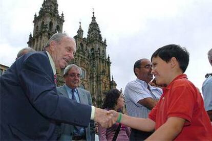 Manuel Fraga saluda a un niño en la plaza del Obradoiro, en Santiago de Compostela.