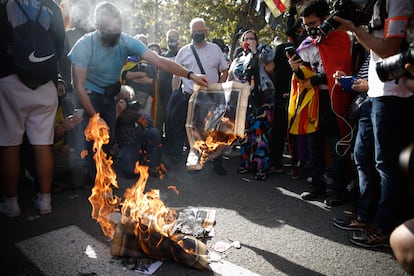 Manifestantes independentistas queman fotografías de Felipe VI y el presidente del Gobierno, Pedro Sánchez, durante la concentración de protesta por su presencia en Barcelona, el 9 de octubre de 2020.