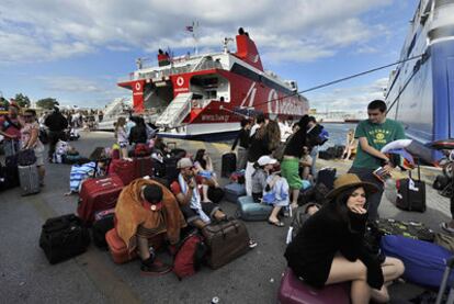 Turistas sentados junto a sus pertenencias, ayer en El Pireo.