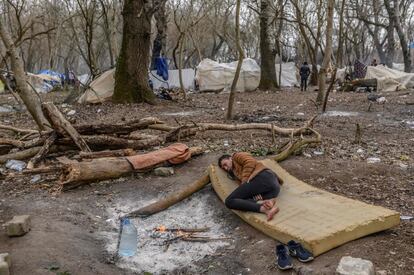 Un migrante descansa cerca de una hoguera en el bosque en la frontera entre Turquía y Grecia, cerca del paso fronterizo de Pazarkule en Edirne (Turquía).