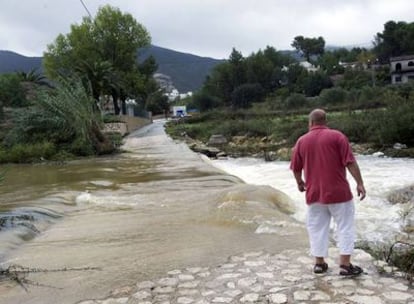 Un vecino observa el acceso a las urbanizaciones de La Solana y Valle Paraíso, cortado por la crecida de un barranco, ayer, en Xaló.