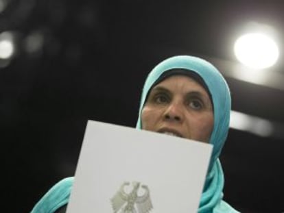 Una mujer nacionalizada sostiene los documentos de su ciudadanía alemana.