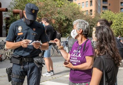 Un policía identifica, a las puertas de la Ciudad de la Justicia de València, a una participante en la concentración de apoyo a una de las feministas sancionadas por la huelga del 8M de 2018.