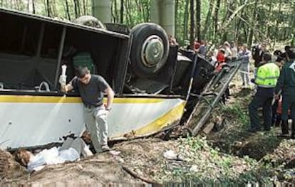 Unos operarios intentan asistir a los ocupantes del autobús accidentado ayer.