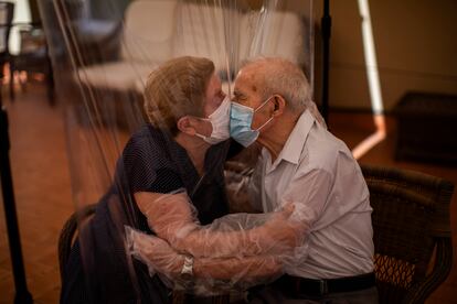 Agustina Cañamero, de 81 años, y Pascual Pérez, de 84, se abrazan y besan a través de una pantalla de película plástica para evitar contraer el nuevo coronavirus en un asilo de ancianos en Barcelona, España, el lunes 22 de junio de 2020,en el centro de ancianos Ballesol Fabra i Puig.