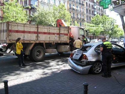 Un agente de la Policía Municipal revisa el vehículo arrastrado por el camión grúa.