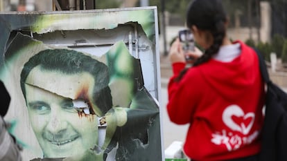 Una mujer hace una fotografía a una imagen quemada de Bachar el Asad en Qamishli (Siria), el 8 de diciembre.