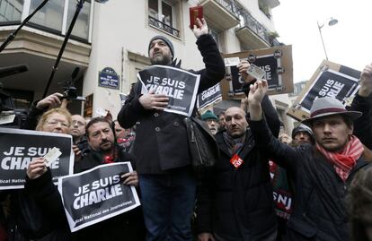 Jornalistas exibem cartazes e identificação de imprensa durante um minuto de silêncio em frente à redação de Paris do semanário satírico Charlie Hebdo.