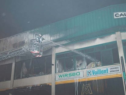 Un bombero apaga una de las naves que resultó afectada por el incendio.