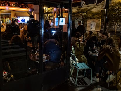 Clientes en un café de París siguen este miércoles el discurso televisado del presidente Macron en el que anuncia un nuevo confinamiento en Francia.