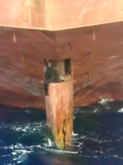 Un hombre durante su travesía subido a la pala del timón de un carguero.