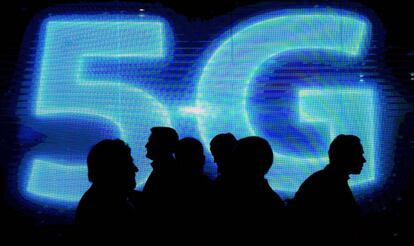 Varias personas pasan junto a un logo luminoso de 5G en el último Mobile World Congress, en Barcelona.