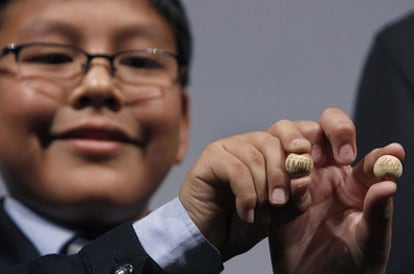 Un niño de San Ildefonso muestran la bola del número 58.268, premiado con el Gordo del sorteo de Navidad