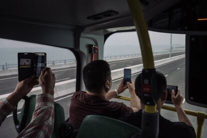 Varios pasajeros hacen fotos durante uno de los primeros trayectos de un autobús hacia Zhuhai sobre el nuevo macropuente que conecta a Hong Kong con Macao y Zhuhai, en la costa sur de China.