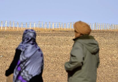 En 1976, España abandonó su colonia del Sáhara Occidental. Marruecos y Mauritania se repartieron el territorio que dejó España. El Frente Polisario, que había sido fundado tres años antes con el objetivo de alcanzar la independencia respecto a España, declaró la guerra a los dos países. Conforme el Ejército marroquí avanzaba sobre las ciudades del Sáhara decenas de miles de saharauis -entre 60.000 y 150.000, según las partes enfrentadas- se exiliaron en unos campamentos que levantaron cerca de la ciudad argelina de Tinduf. El entonces rey de Marruecos, Hassan II, comenzó a construir el muro en los años ochenta. Diez años después, en 1991 el Frente Polisario y Rabat firmaron la paz bajo el auspicio de la ONU y con el compromiso mutuo de colaborar en la organización de un referéndum de autodeterminación. El muro siguió creciendo. A medida que pasaron los años, la comunidad internacional se fue olvidando del conflicto del Sáhara, Marruecos relegó la opción del referéndum en favor de una autonomía y las decenas de miles de exiliados al otro lado del muro continuaron viviendo en condiciones paupérrimas y con una dependencia absoluta de la solidaridad internacional. El muro alcanza hoy los 2.700 kilómetros de longitud. Y sigue generando polémica. De hecho, el ministerio de Comunicación marroquí, del islamista Partido Justicia y Desarrollo, ha emitido un comunicado dirigido a la agencia France Presse donde señala que esta obra militar no es “un muro de separación”, tal como afirmaba la agencia, porque, “hay un punto de paso operacional abierto a las poblaciones”. Y añade el escrito: “El muro defensivo de arena ha sido construido para garantizar el derecho de Marruecos a la preservación de su seguridad y para luchar contra el uso del Sáhara como paso de las redes terroristas, el tráfico de seres humanos y de la droga”. Desde el Frente Polisario, sin embargo, se afirma que no existe ningún paso que permita a la población saharaui acceder al Sáhara Occidental a través del muro, y que esta obra, que en realidad está compuesta de “siete muros”, es “la mayor barrera creada por el hombre después de la muralla china”. “Se estima que existen siete millones de minas a lo largo del muro, la mayor parte de ellas colocadas por Marruecos del lado Saharaui”, informa una fuente del Frente Polisario./ FRANCISCO PEREGIL (Rabat)