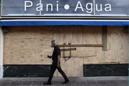 Un hombre camina frente a una tienda cerrada en Puerto Rico protegida contra el huracán María. El Centro Nacional de Huracanes de Estados Unidos (NHC) ha destacado que 'María' es "potencialmente catastrófico" y en Puerto Rico se ha declarado el estado de emergencia.