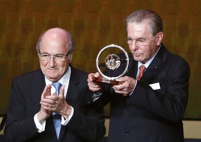 El expresidente del Comite Olímpico Internacional acques Rogge sujeta el galardón presidencial de la FIFA, entregado por Joseph Blatter, presidente del organismo internacional.