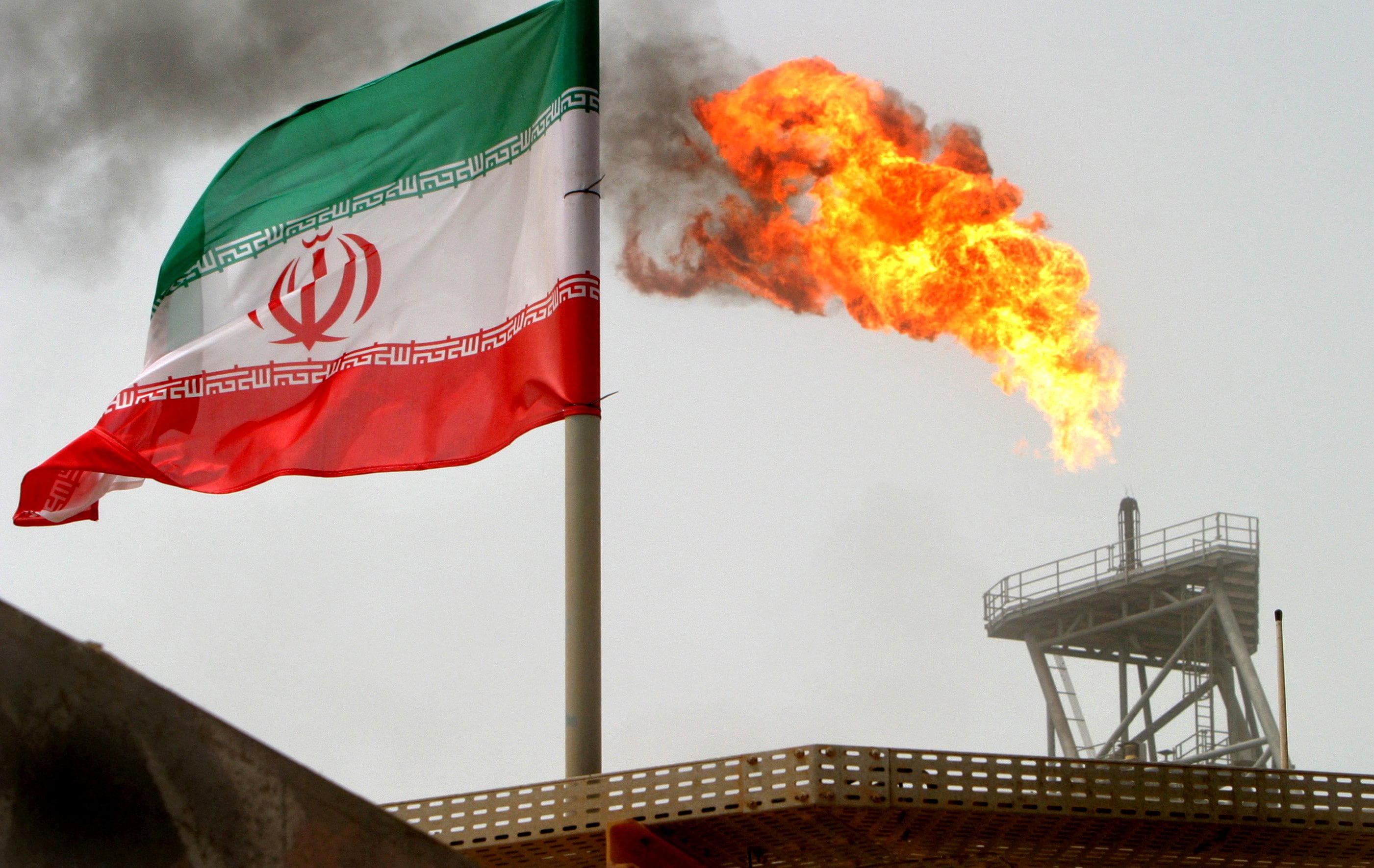 Una bandera iraní junto a una plataforma de producción de petróleo