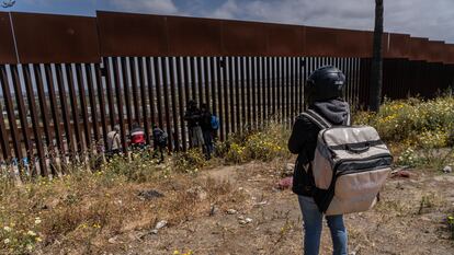 Migrantes piden comida a un costado del muro que divide Tijuana con San Diego, en 2023.