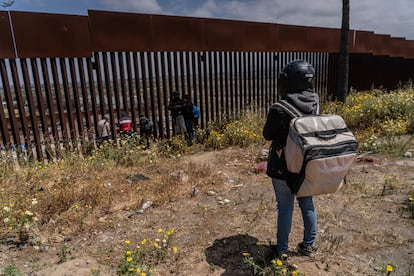 Migrantes piden comida a un costado del muro que divide Tijuana con San Diego, en 2023.