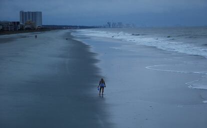 Una mujer busca conchas antes de la llegada del huracán Florence en Surfside Beach, Carolina del Sur.