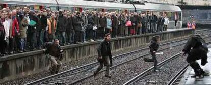 Algunos viajeros que van al trabajo saltan a las vías mientras otros aguardan en el andén de la estación de Saint Lazare, en París.