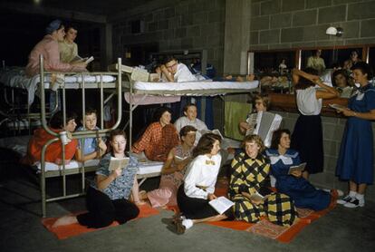 A girl plays an accordion as others on bunks sing in a 4-H dormitory, Iowa
