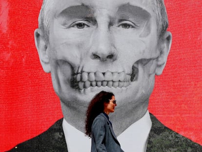 A woman walks past a satirical portrait of Vladimir Putin during an exhibition against the Russian invasion of Ukraine in Bucharest, Romania.
