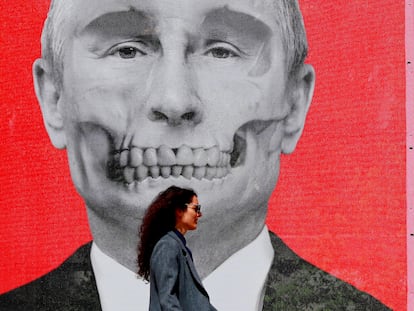 Una mujer pasa delante de un retrato del presidente ruso, Vladímir Putin, caracterizado como una calavera, durante una exposición en contra de la ofensiva militar rusa en Ucrania, en la plaza del Rey de Bucarest (Rumania) el 29 de abril.