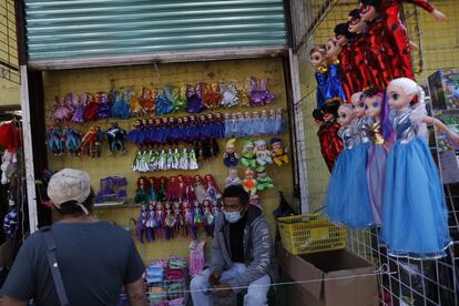 Un comprador mira un puesto callejero que vende muñecas, mientras la gente compra regalos para el Día de Reyes en el centro de Ciudad de México, este martes.