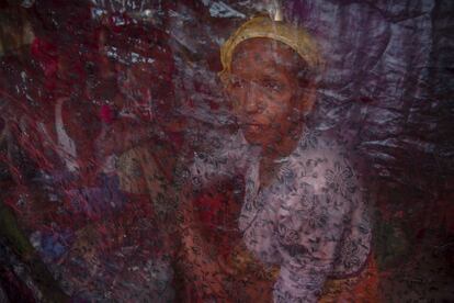 Una mujer musulmana rohingya es vista a través de una tela que protege su refugio de las lluvias en un campo de refugiados en Bangladesh.