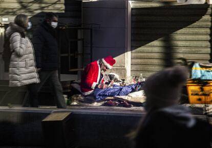 Una persona sin hogar vestido de Santa Claus se refleja en el escaparate de una tienda en Milán (Italia), el 13 de diciembre de 2020.