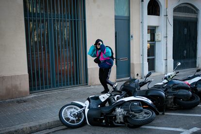 Una chica tapándose del viento camina junto a una ilera de motos caídas a causa del viento en el barrio de Poble Nou,  en Barcelona.
