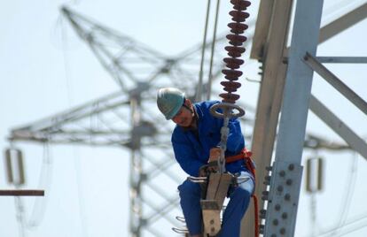Un trabajador instala nuevas líneas de alto voltaje en una torre de electricidad.