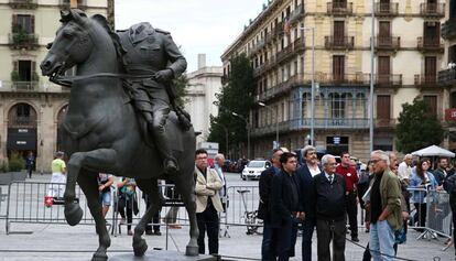 La estatua ecuestre del dictador al lado de los organizadores de la exposición.