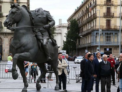 La estatua ecuestre del dictador al lado de los organizadores de la exposición.