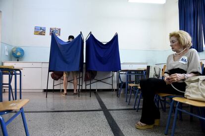 Un hombre voto junto a una observadora electoral con una pegatina en su blusa a favor del 'Si' en un colegio electoral en Salónica (Grecia).