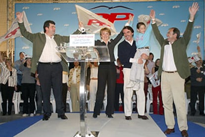 José María Aznar, con un niño en brazos, junto a Esperanza Aguirre, ayer, en un mitin de la campaña del PP.