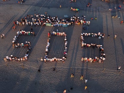 Los vecinos y veraneantes de Sagunto y Canet formaron ayer las letras SOS en la playa que limita ambos municipios.