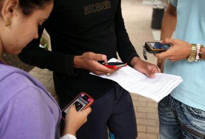 Tres j&oacute;venes usan sus tel&eacute;fonos m&oacute;viles.