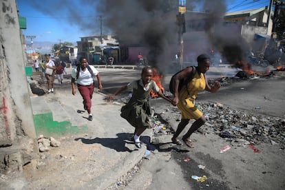 Una mujer y su hija pasan corriendo frente a una barricada levantada por la policía en protesta por la mala gestión policial en Puerto Príncipe (Haití), el 26 de enero de 2023.