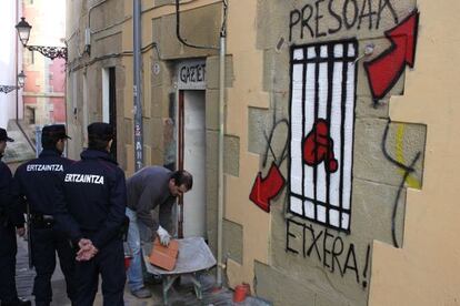 Dos 'ertzainas' supervisan el tapiado de la casa Uxotegi, despus de que los asaltantes la abandonaran el pasado mes de diciembre.